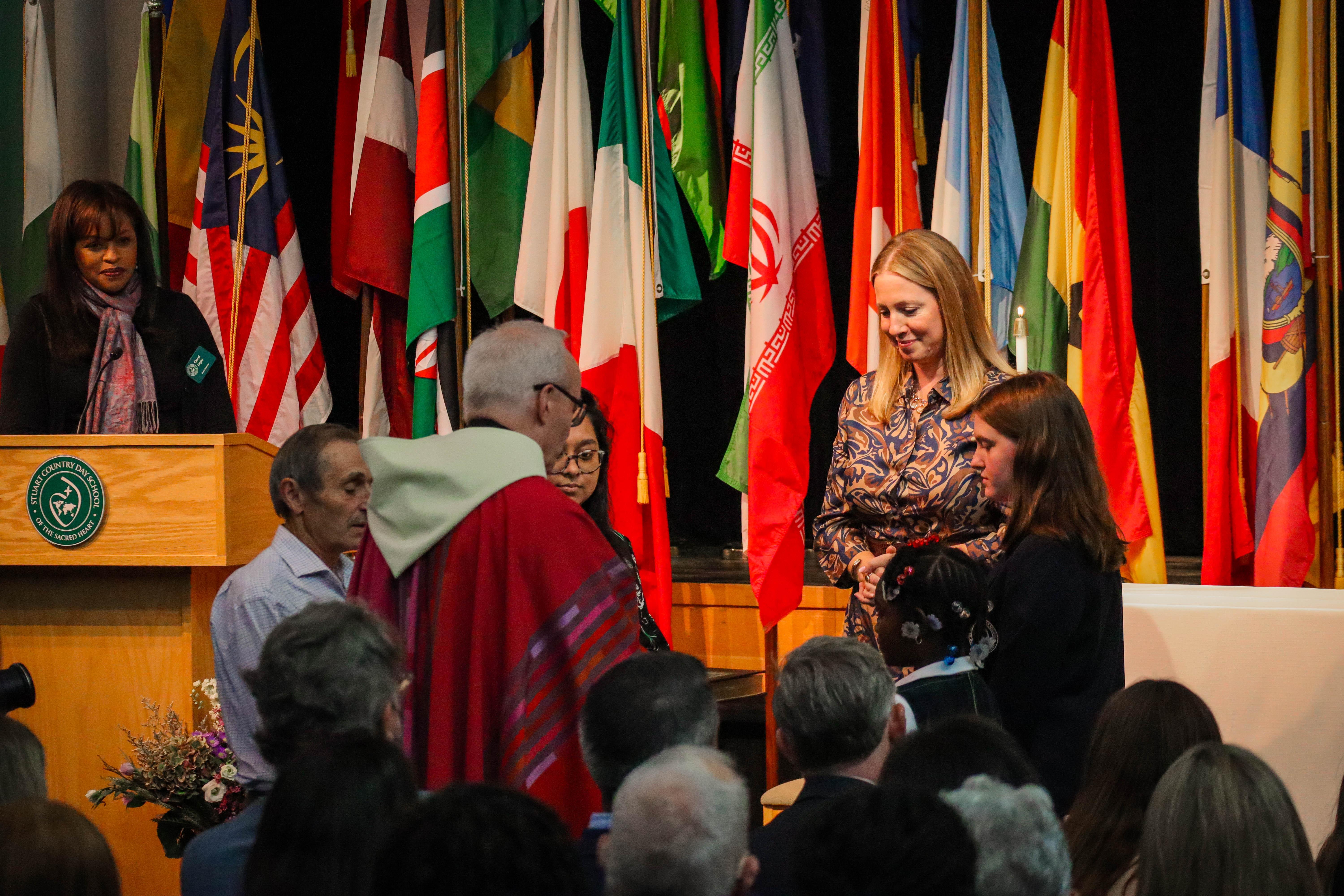 The installation blessing of Julia Breen Wall (right) by Monsignor Gregory Malovetz along with a student and staff member who were part of the school's previous head's installation 11 years ago.  (Photo courtesy of Stuart Country Day School)