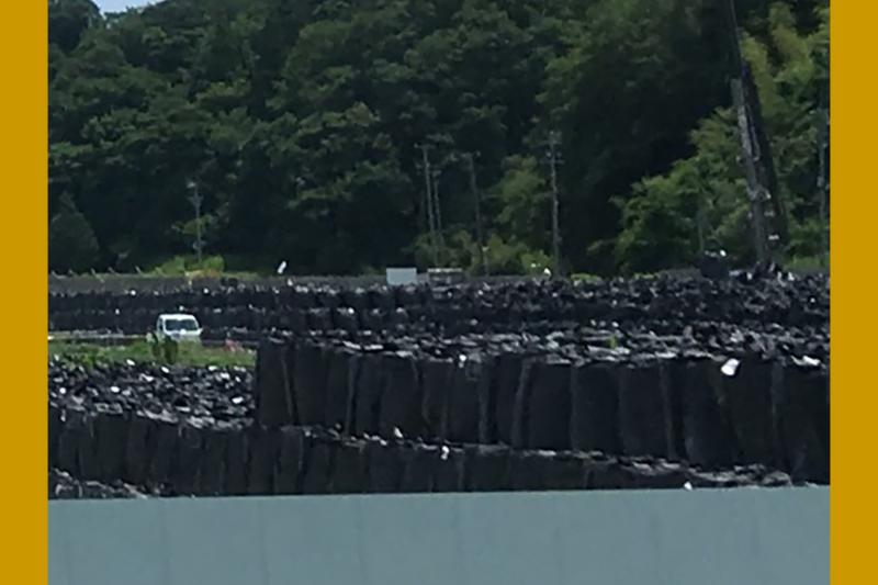 Piles de sacs noirs remplis de déchets et de sols contaminés par la radioactivité, s’étendant à perte de vue. Piles de sacs noirs remplis de déchets et de sols contaminés par la radioactivité, s’étendant à perte de vue.